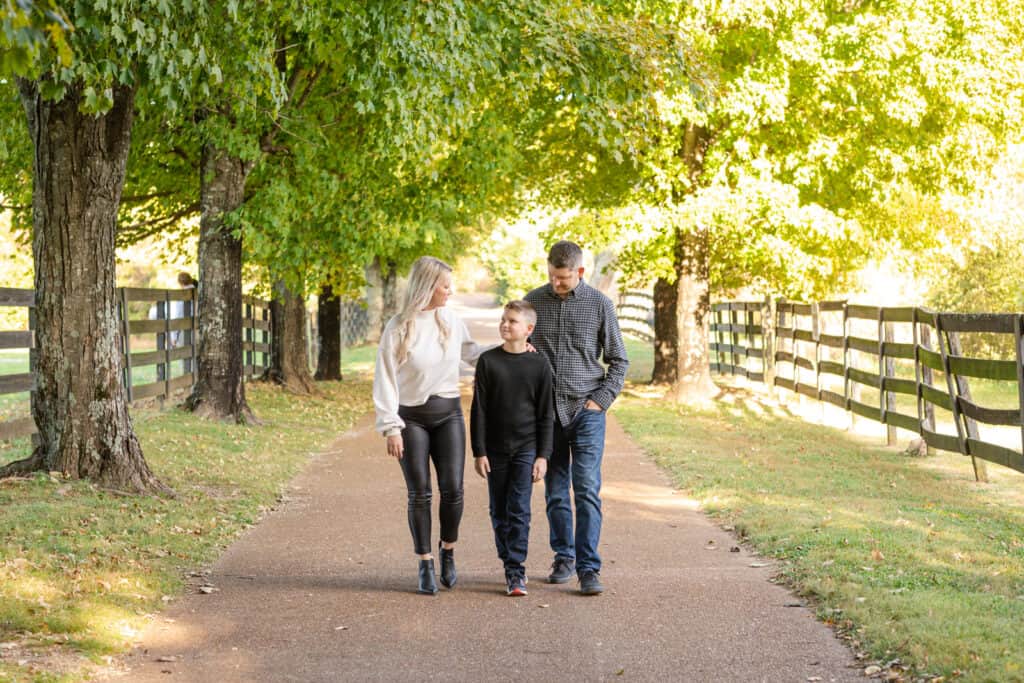 Family of three walk down wooded lane